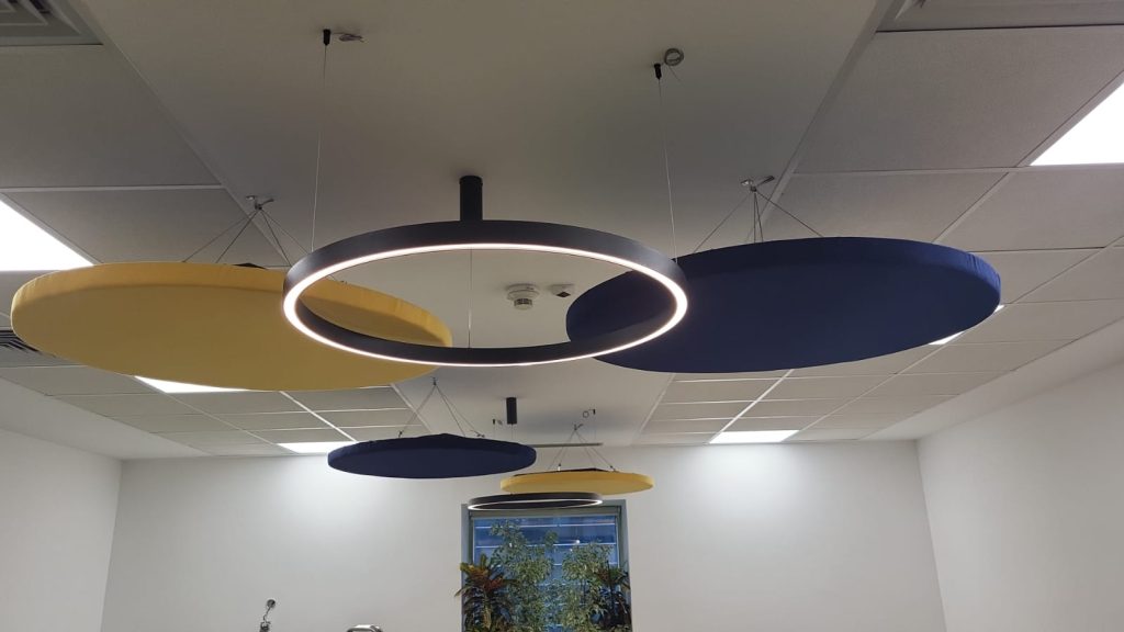Amenajare cu panouri tapitate openspace in combinatie cu corpuri de iluminat albastru si galben